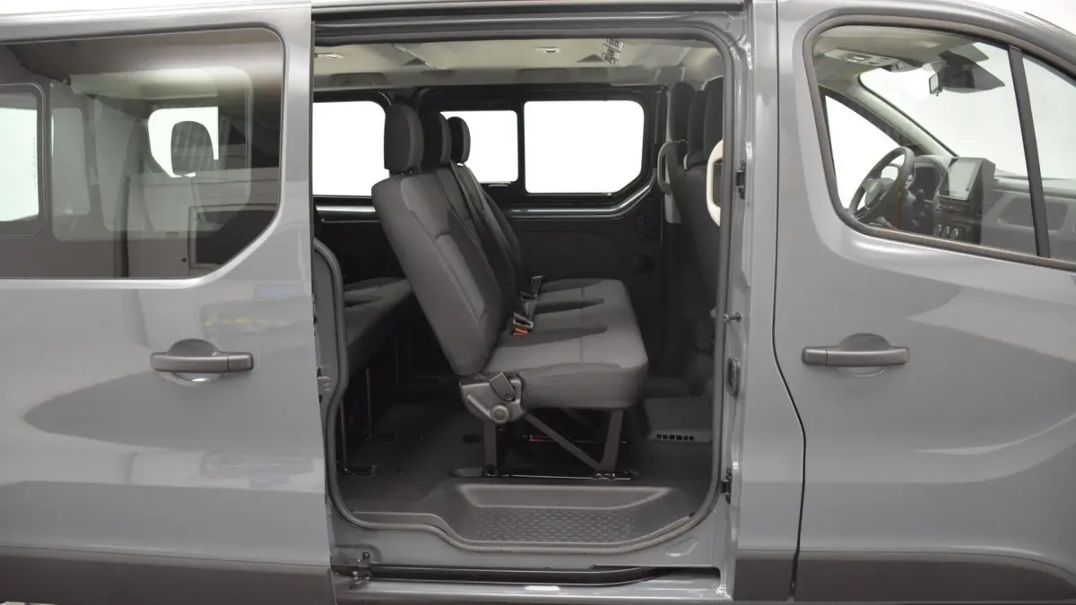Vue latérale droite du Renault Trafic Fourgon gris clair 2025 avec porte coulissante ouverte montrant la banquette arrière 3 places.