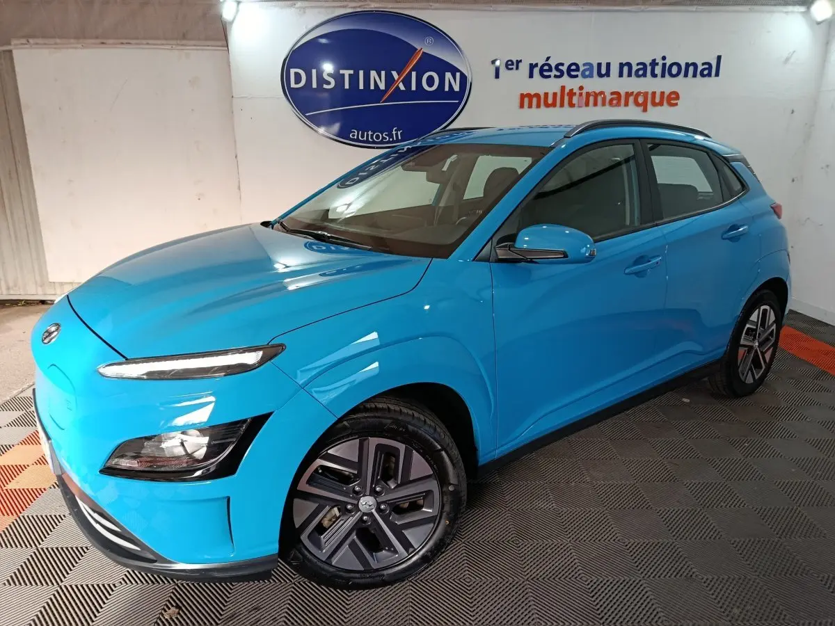 Vue 3/4 avant d'un Hyundai Kona électrique bleu vif avec jantes spécifiques et rétroviseurs assortis.