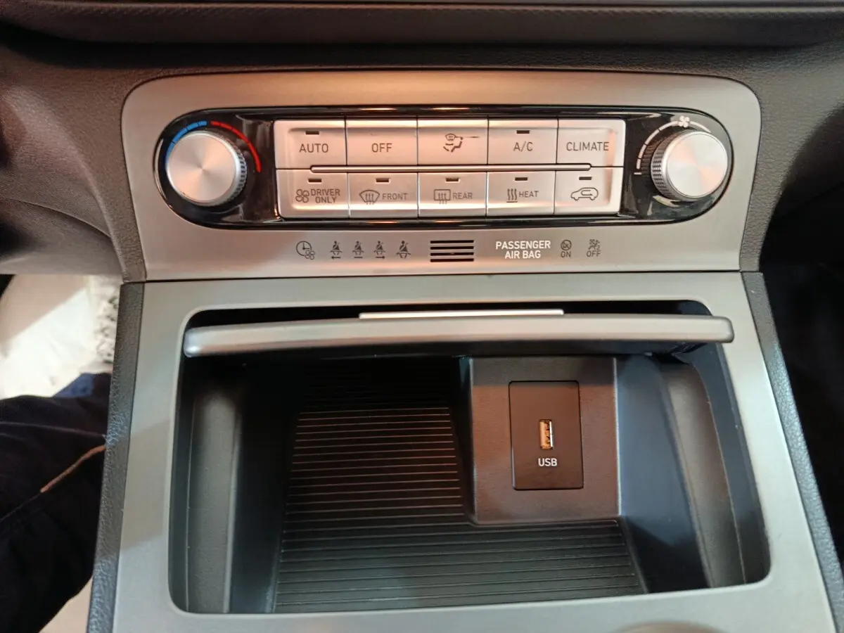 Vue rapprochée de la console centrale du Hyundai Kona électrique 2022, avec commandes climatisation et prise USB visible.