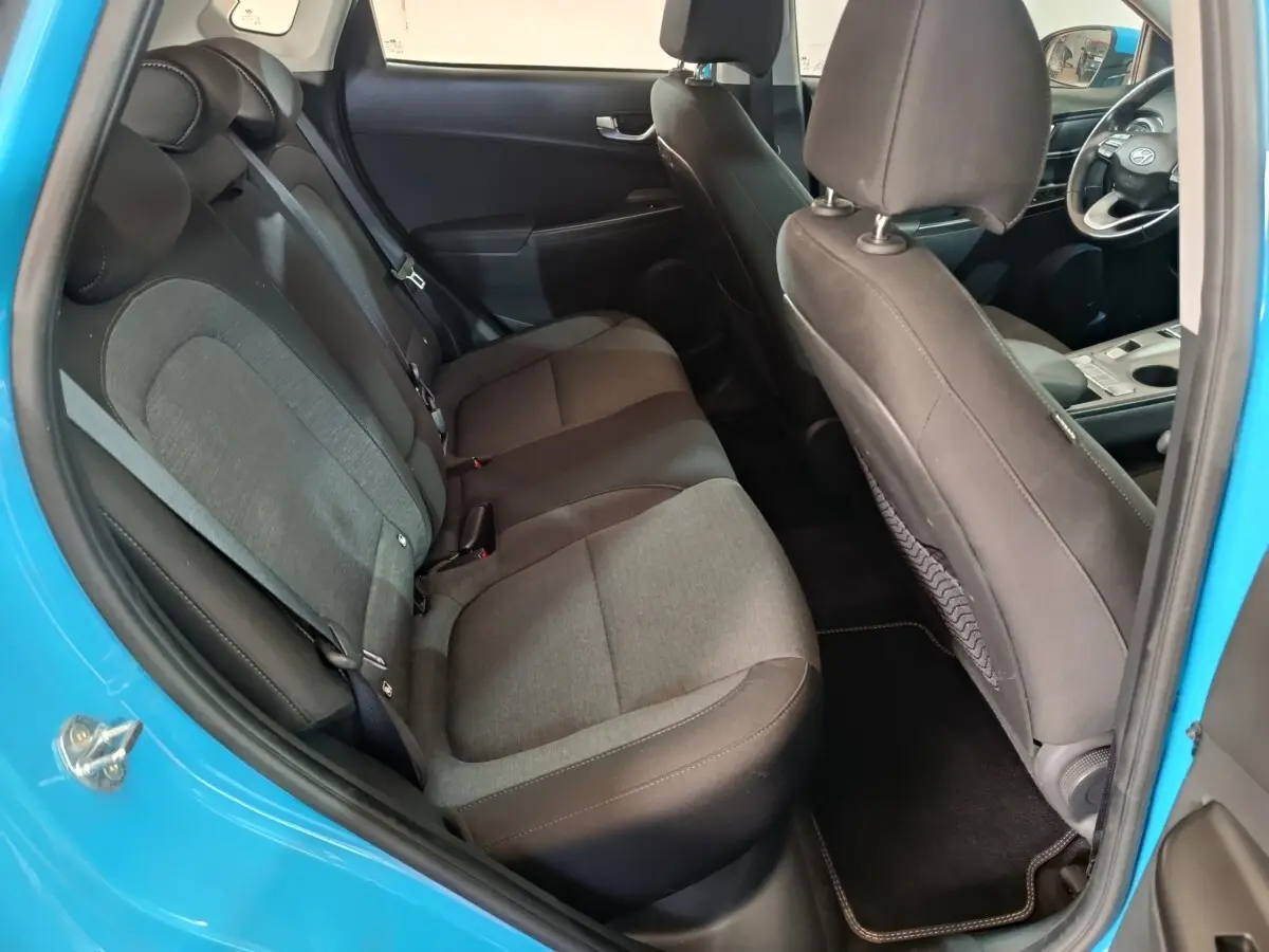 Vue intérieure côté gauche montrant la banquette arrière grise et noire du Hyundai Kona électrique bleu 2022.