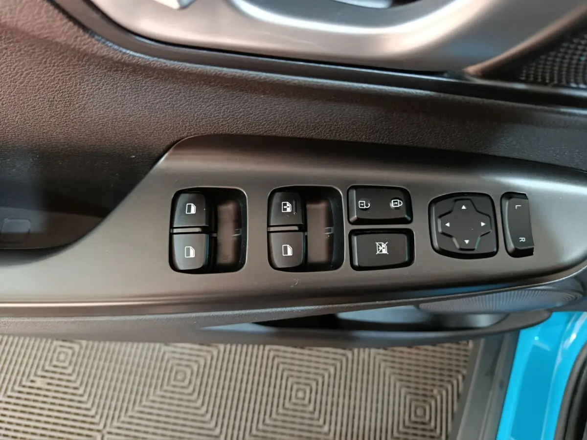 Vue rapprochée des commandes de porte côté conducteur du Hyundai Kona bleu électrique, avec boutons de réglage des vitres et rétroviseurs.