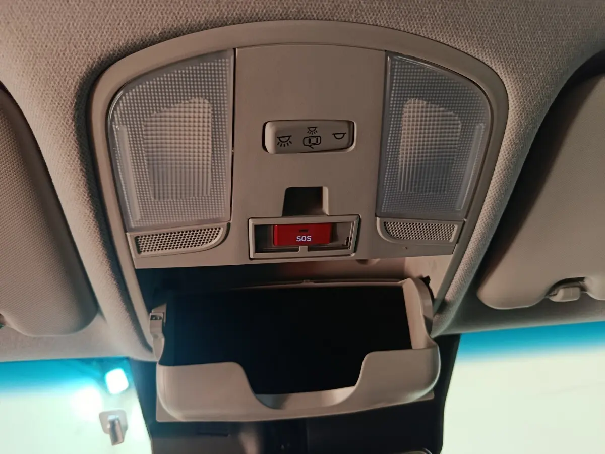 Vue intérieure du plafonnier avant avec éclairages, bouton SOS rouge et rangement lunettes ouvert dans une Hyundai Kona bleu électrique.