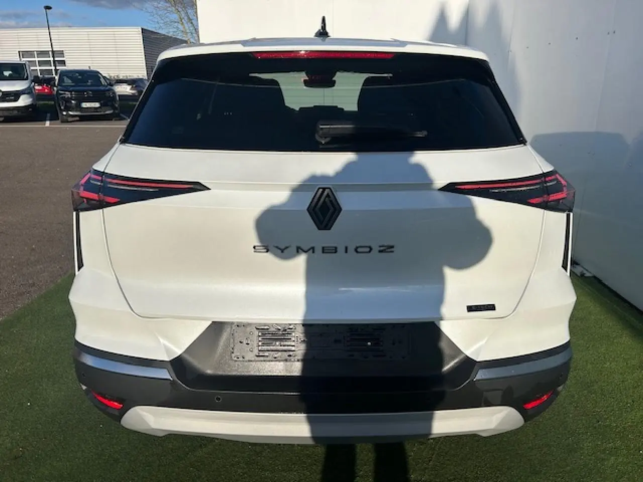 Vue arrière d’un Renault Symbioz blanc nacré avec feux arrière LED fins et logo noir central.