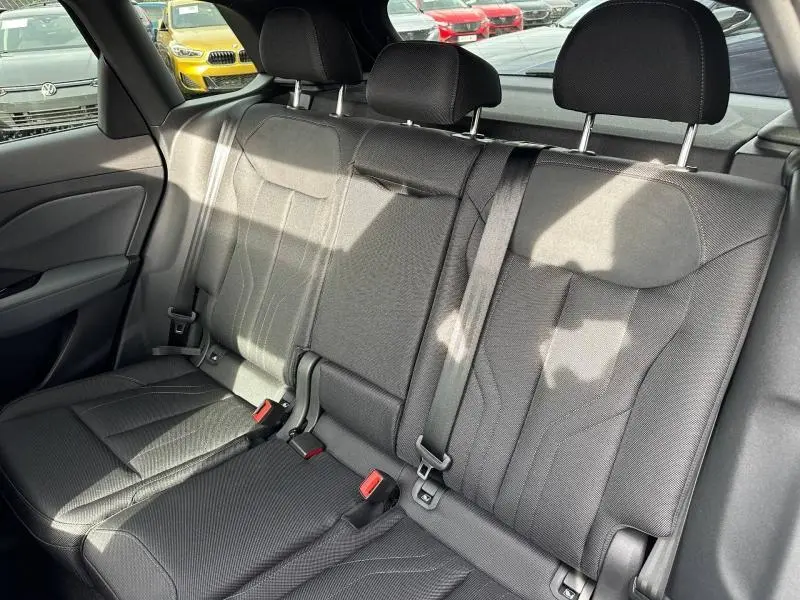 Vue intérieure des sièges arrière noirs en tissu de l'Audi Q3 2026, avec ceintures de sécurité et appuie-têtes visibles.