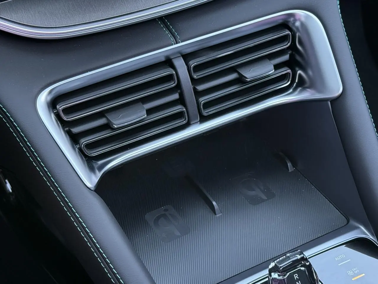 Gros plan sur la console centrale intérieure noire du BYD SEAL U 1.5 DM-i 218 Boost avec prises de ventilation et zone de charge sans fil.