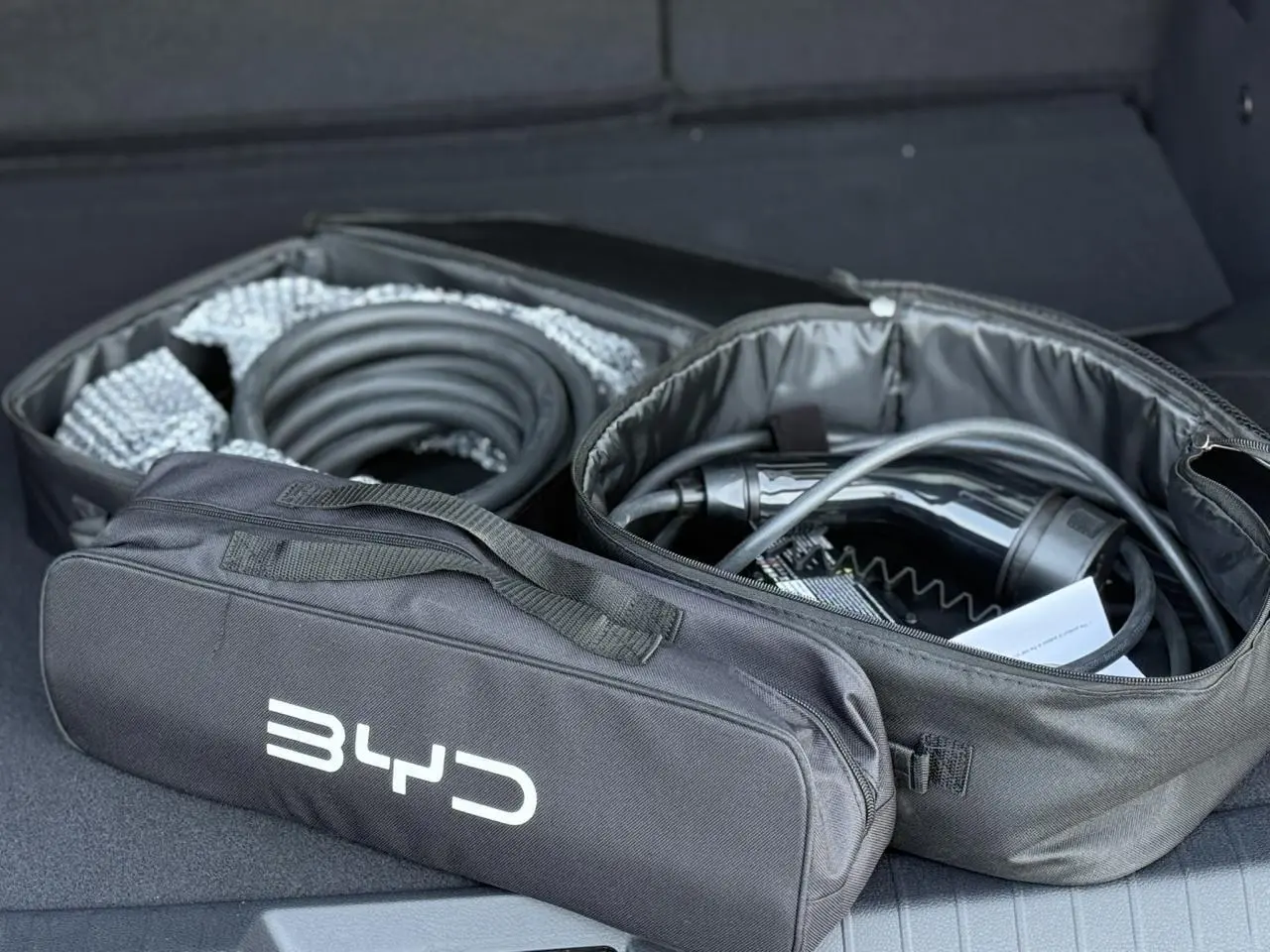 Sac de rangement noir BYD ouvert dans le coffre avec câble de recharge pour BYD SEAL U Snow White.