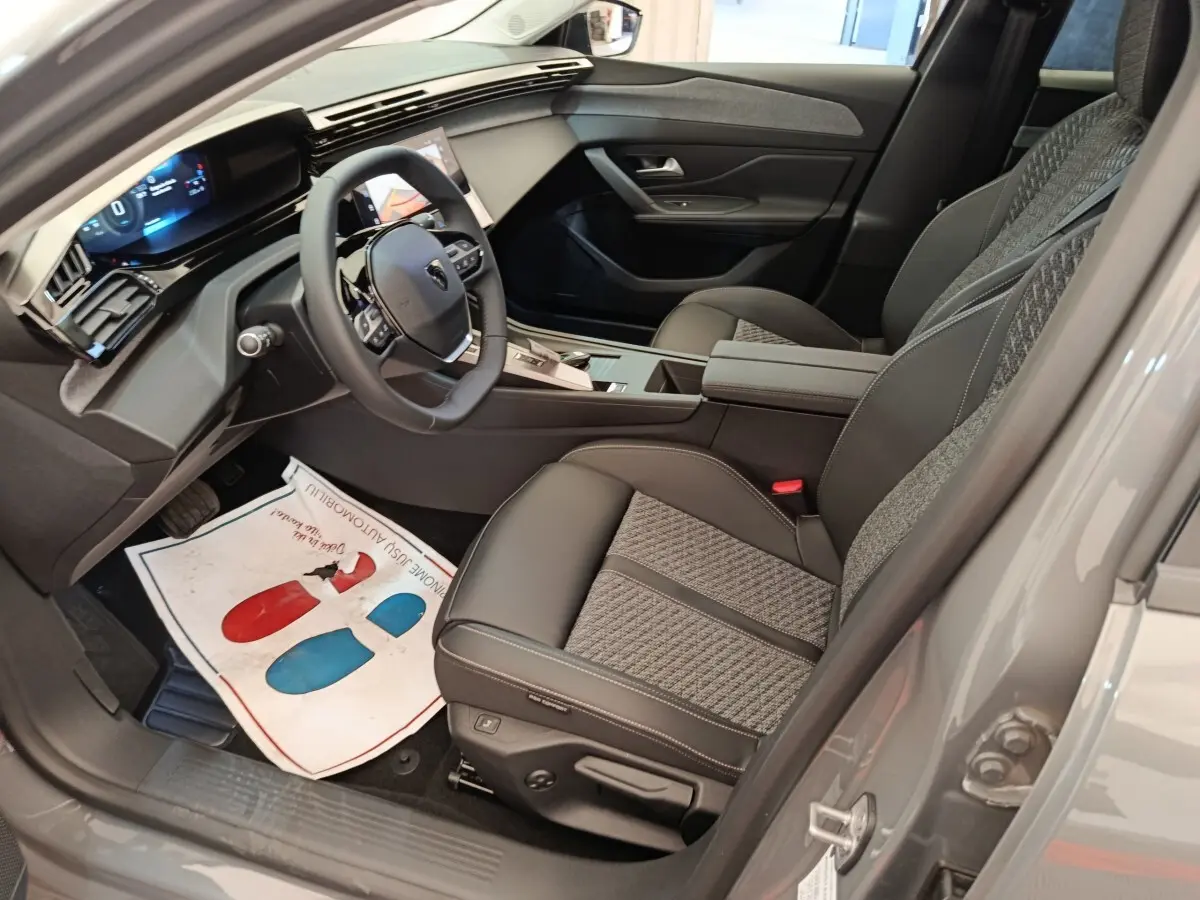 Vue intérieure côté conducteur de la Peugeot 308 gris foncé, volant cuir multifonctions et sièges tissu-cuir bicolores.