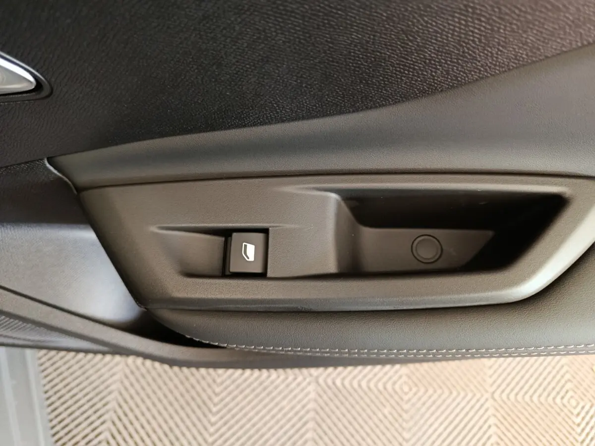 Détail de la commande de lève-vitre sur la porte intérieure noire d'une Peugeot 308 gris foncé, version 2026.
