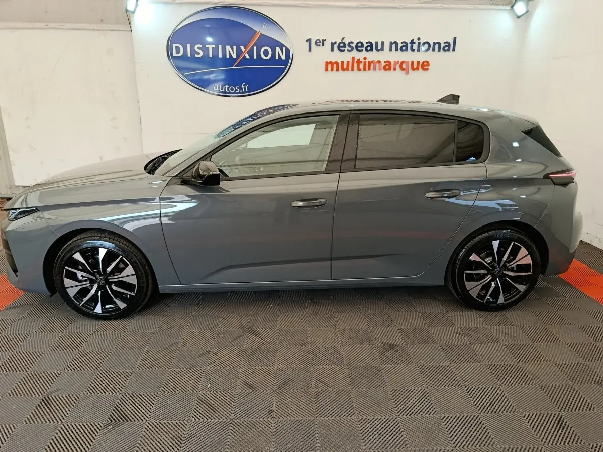 Peugeot 308 BlueHDi 130 gris foncé vue de profil côté gauche, jantes alliage noires et grises, intérieur visible.