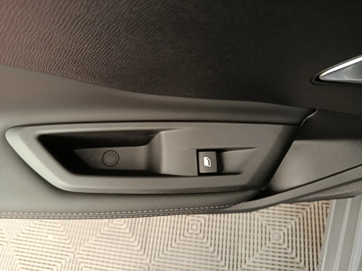 Détail de la commande de lève-vitre côté porte intérieure d’une Peugeot 308 gris foncé, finition cuir.