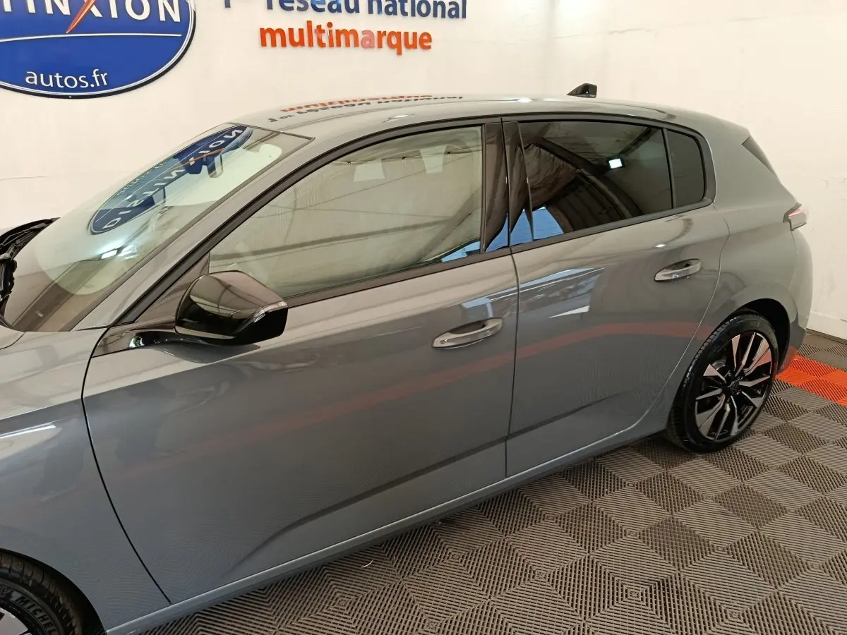 Profil côté gauche d’une Peugeot 308 gris foncé 2026 avec jantes alliage et rétroviseur noir brillant.