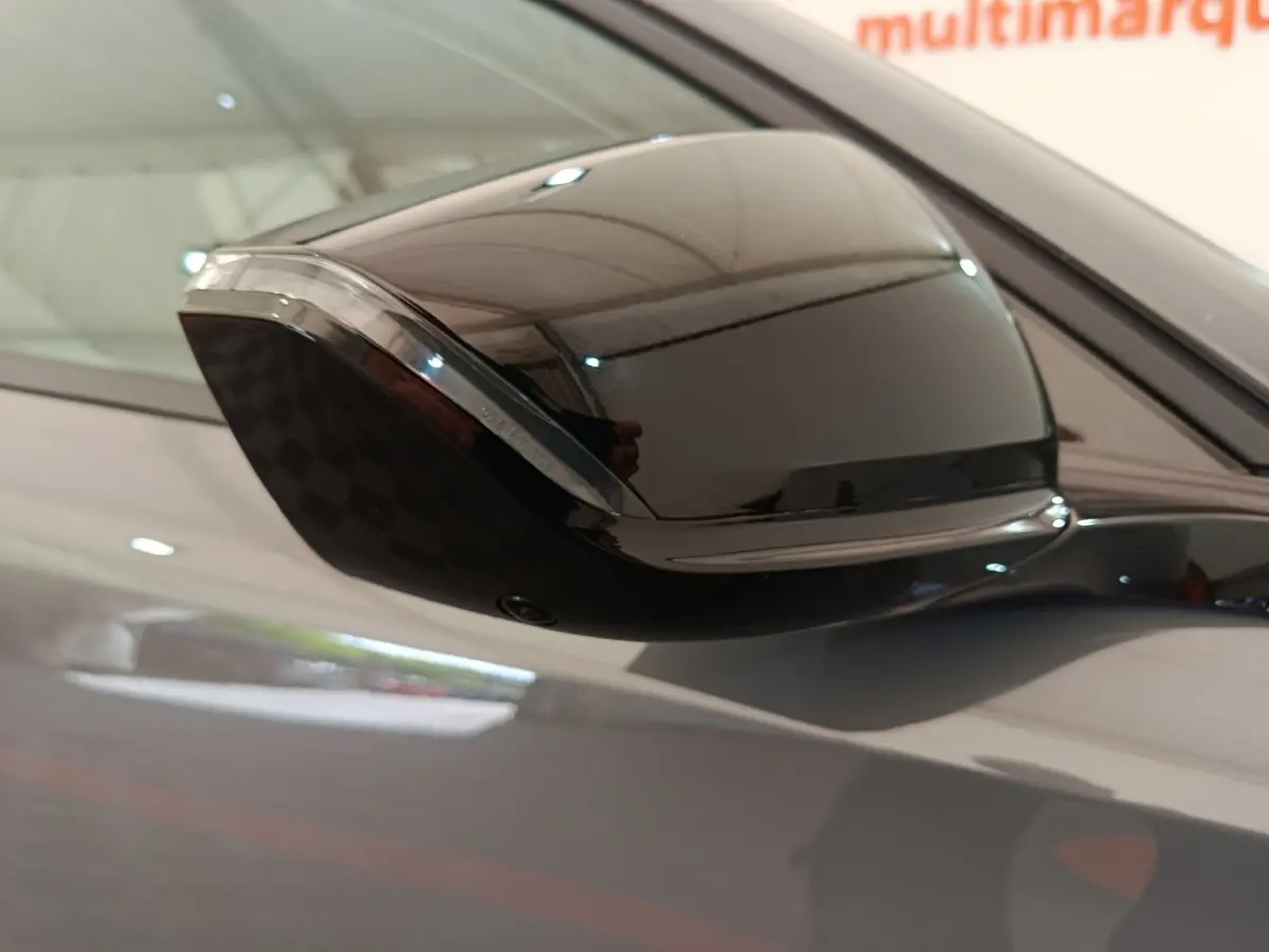 Gros plan sur le rétroviseur droit noir brillant d'une Peugeot 308 gris foncé, reflet de l'environnement intérieur visible.