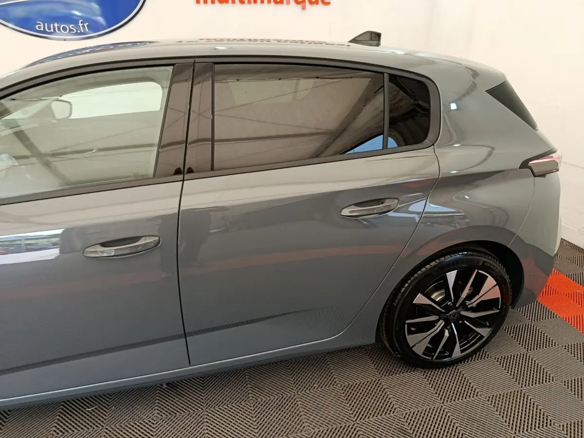 Vue latérale droite d'une Peugeot 308 gris foncé 2026, mettant en valeur les jantes noires et les vitres teintées.