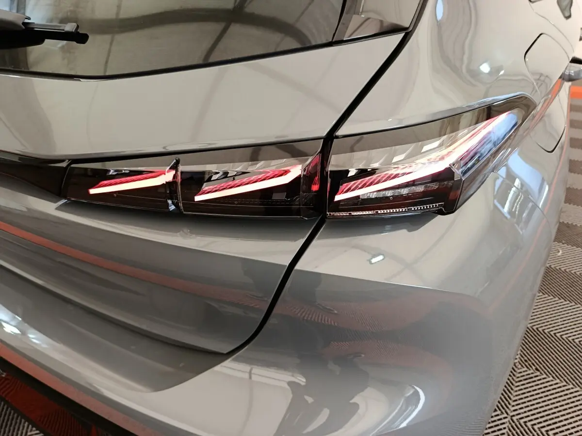 Gros plan sur le feu arrière droit LED d'une Peugeot 308 gris foncé, version 2026, avec lignes lumineuses distinctives.