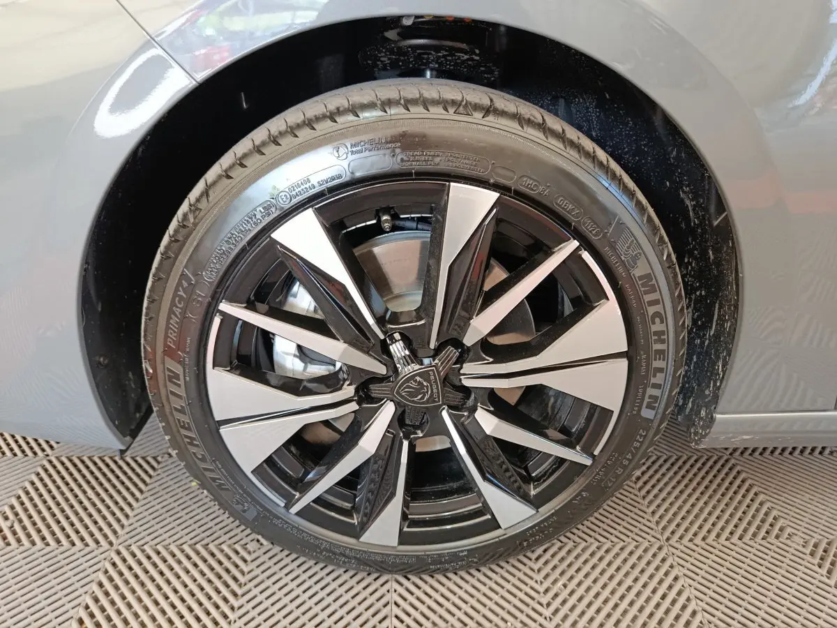 Gros plan sur la roue avant droite de la Peugeot 308 gris foncé, jante alliage noire et argentée au design moderne.