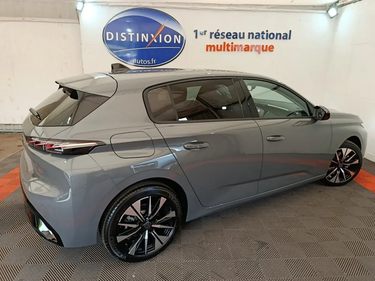 Peugeot 308 BlueHDi 130 gris foncé vue 3/4 arrière droit, jantes alliage noires et feux LED fins.