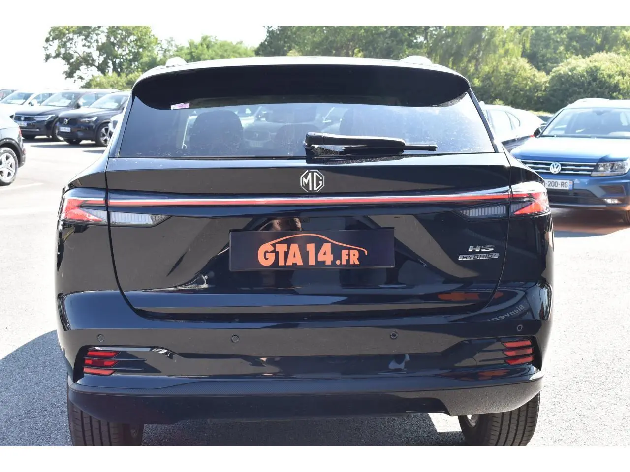 Vue arrière d’un MG MOTOR EHS 1.5 Hybrid+ noir avec feux LED et badge Hybrid visible sur un parking.
