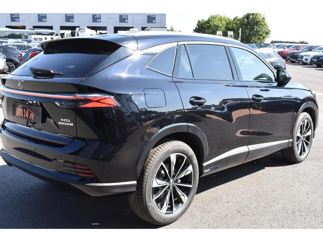 Vue 3/4 arrière droite du SUV MG EHS noir métallisé avec jantes alliage et feux arrière LED allumés.