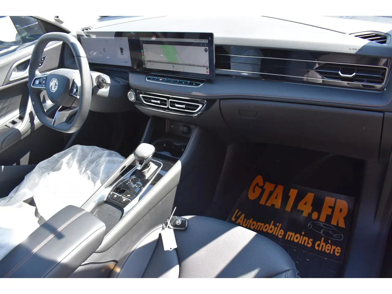 Vue intérieure côté passager du tableau de bord et console centrale du MG Motor EHS 1.5 Hybrid+ noir avec écran tactile panoramique.
