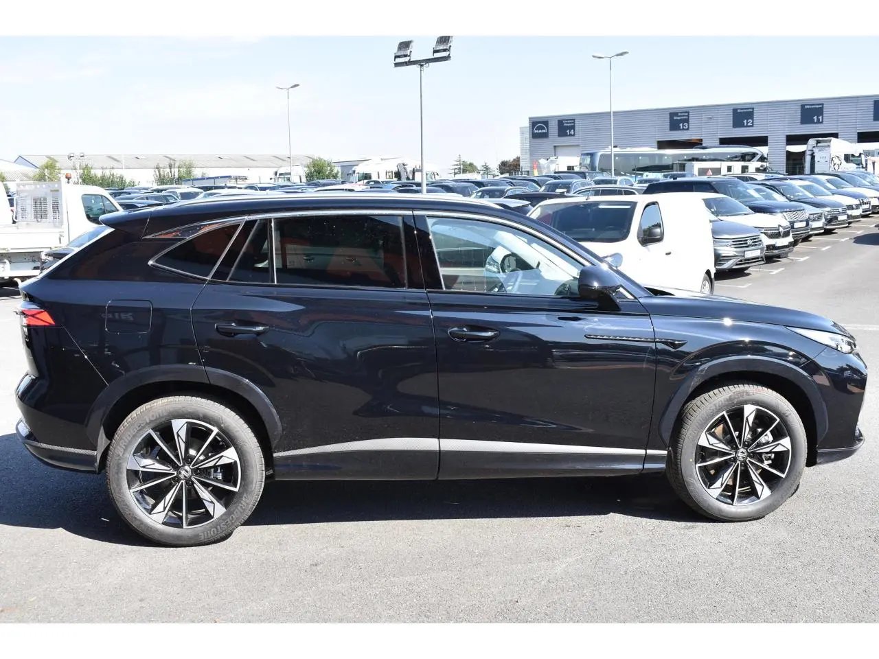 Vue latérale droite du SUV MG EHS noir métallisé avec jantes alliage 19 pouces sur parking extérieur.