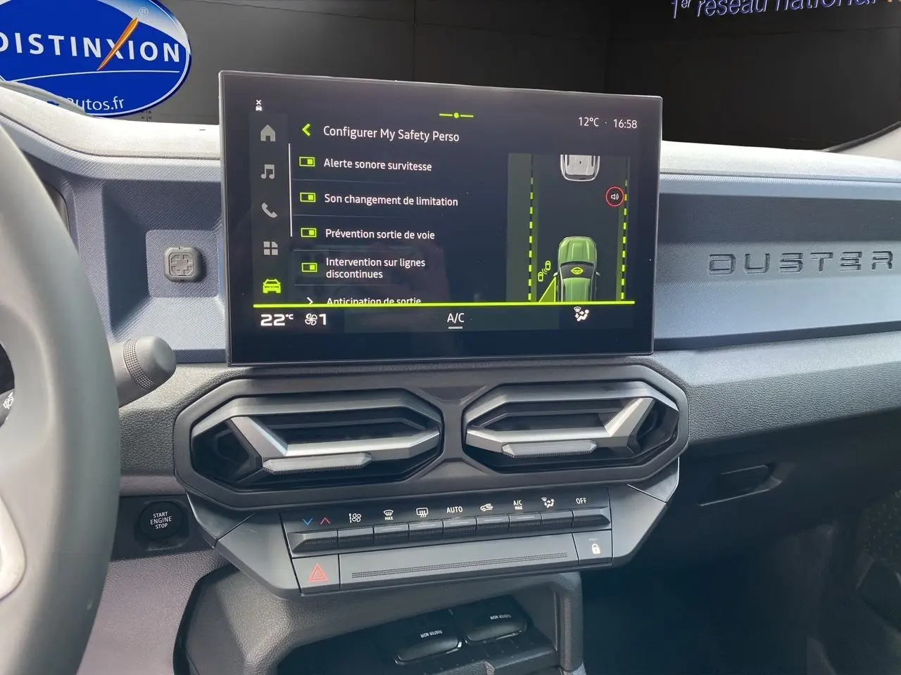 Tableau de bord du Dacia Duster hybride 2025 avec écran tactile affichant les aides à la conduite et aérateurs hexagonaux.