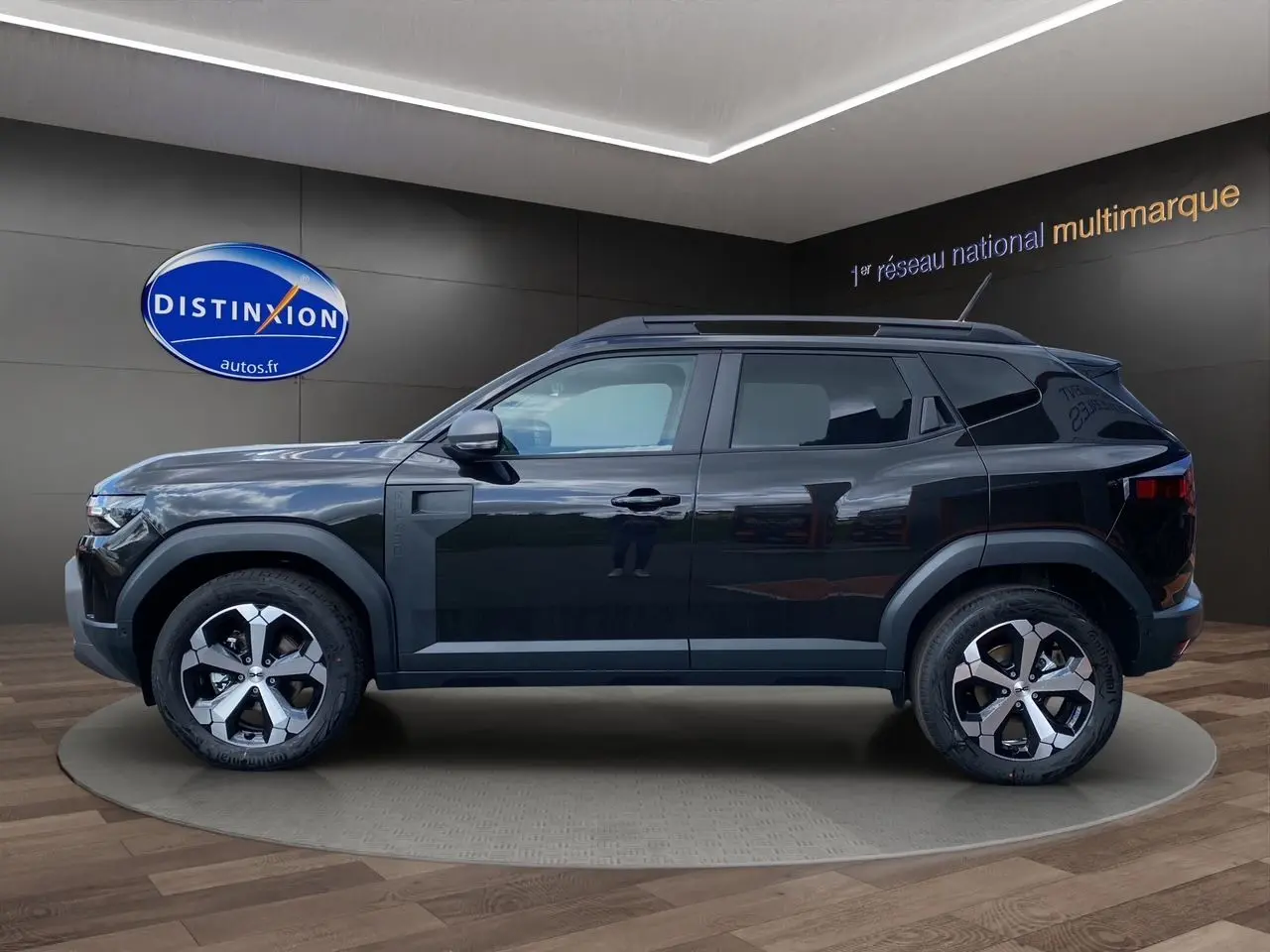 Profil côté gauche du Dacia Duster hybride noir 2025 avec jantes alliage et barres de toit visibles