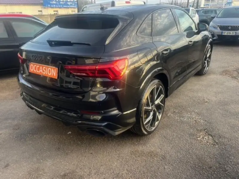 Audi RS Q3 Sportback noir Mythic vue 3/4 arrière droit avec jantes alu distinctives et feux LED allumés.