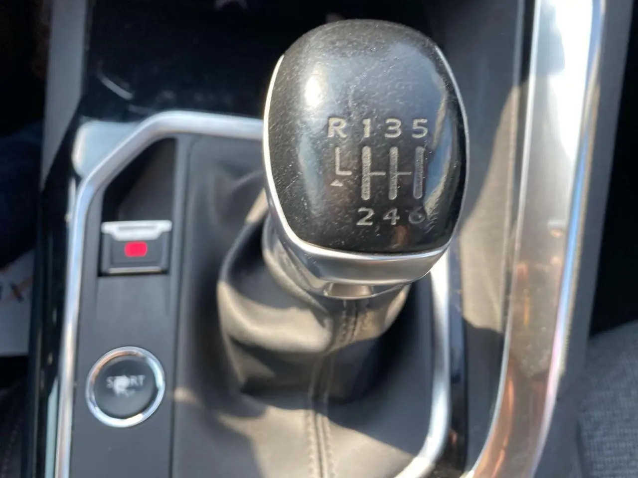 Gros plan sur le levier de vitesse manuel noir du Peugeot 3008 blanc, avec bouton mode Sport visible à gauche.