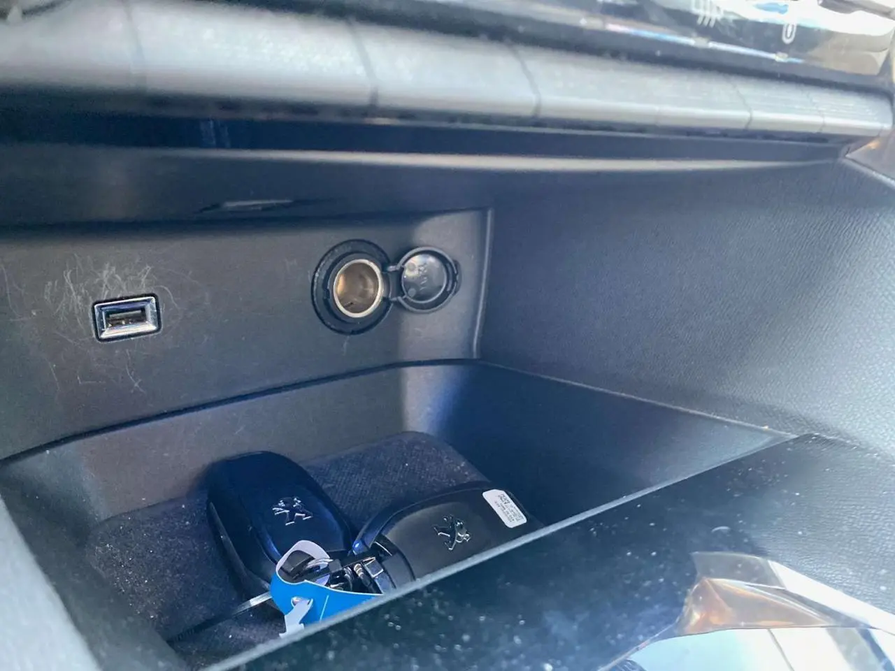 Gros plan sur la console centrale du Peugeot 3008 blanc avec clé mains libres et prise USB visible