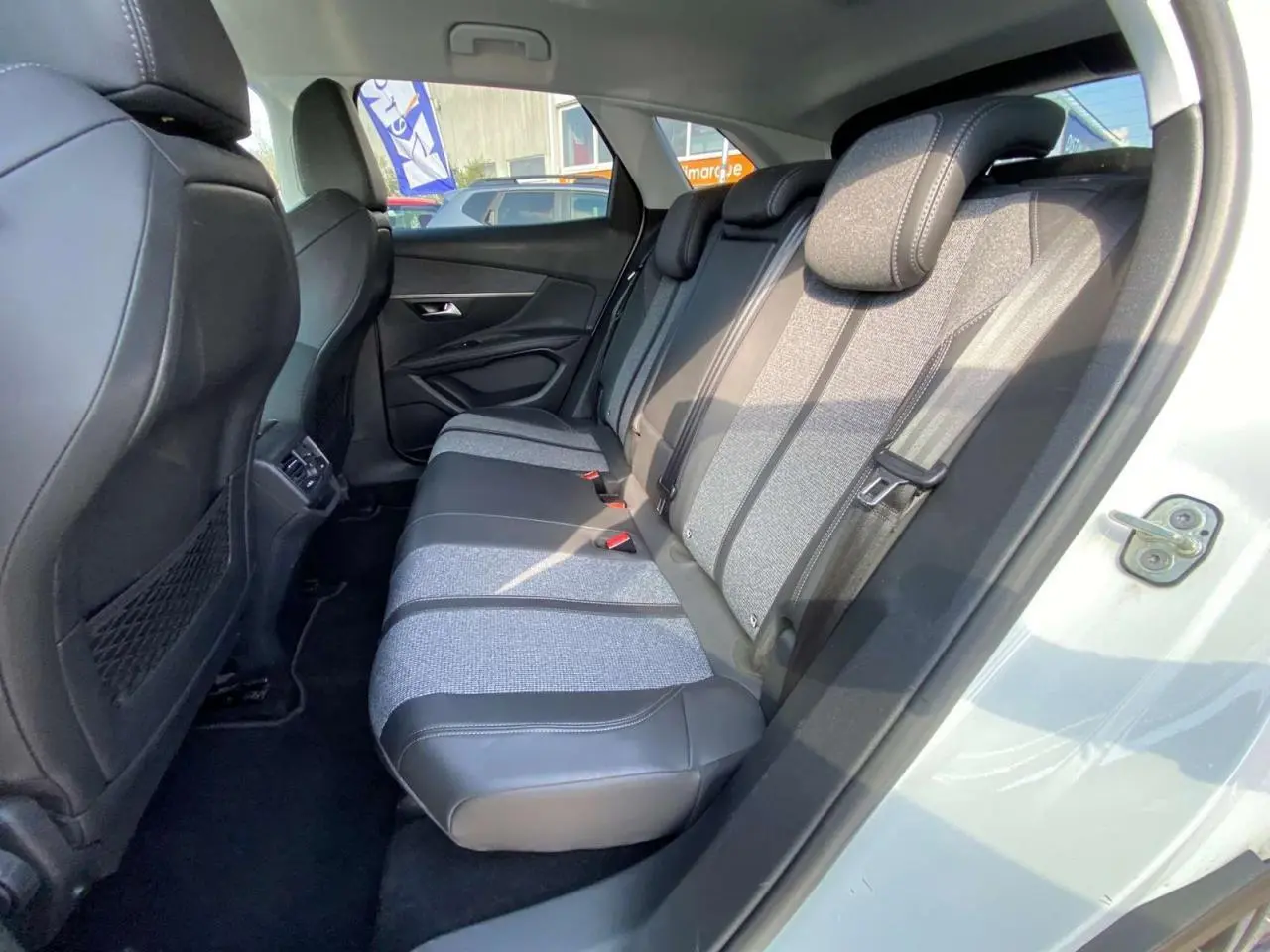 Vue intérieure côté droit montrant la banquette arrière bi-matière grise et noire du Peugeot 3008 blanc de 2018.