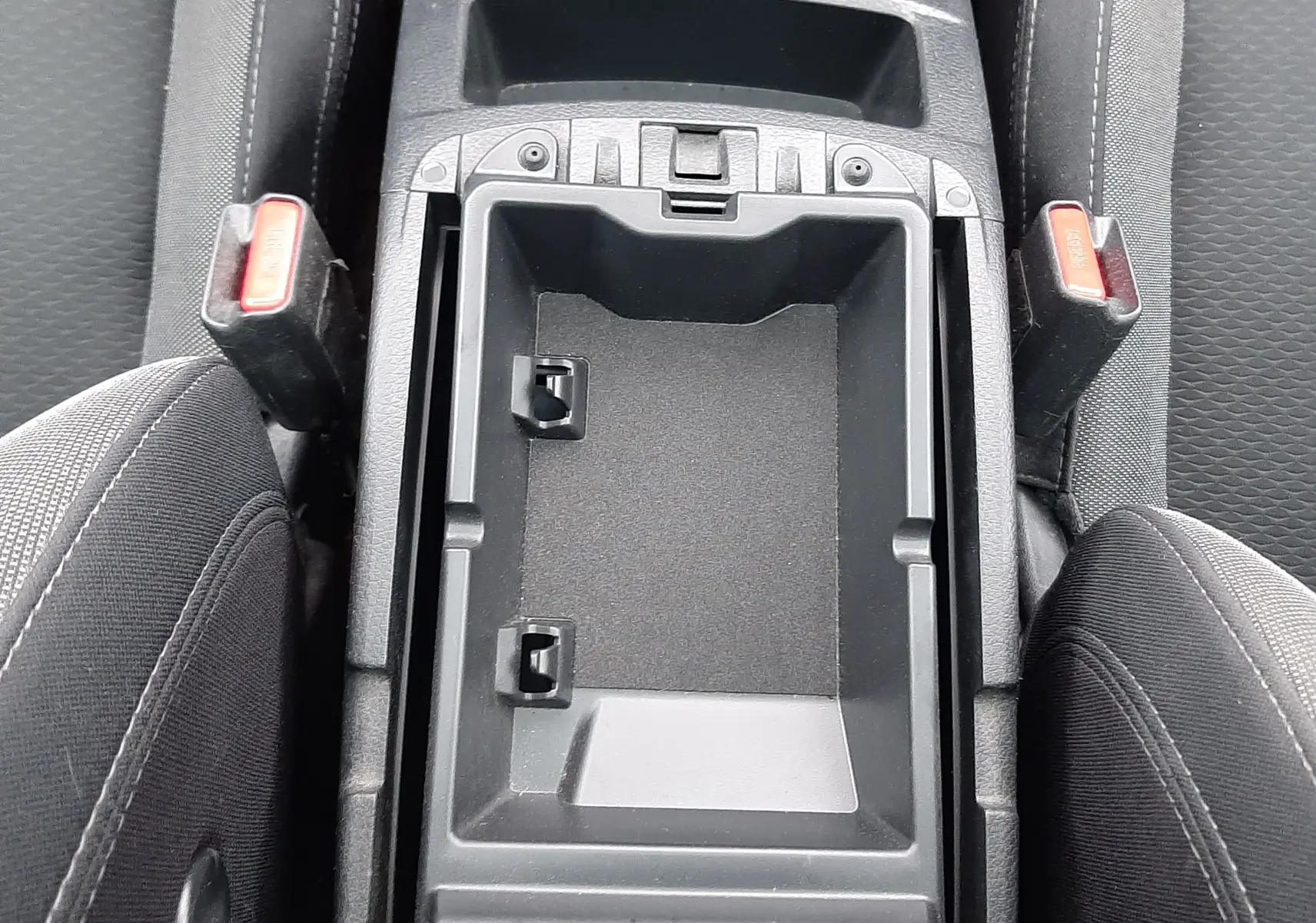 Vue plongeante sur le rangement central noir entre les sièges avant en tissu gris du Nissan Qashqai DCI 115 N-Connecta 2020.