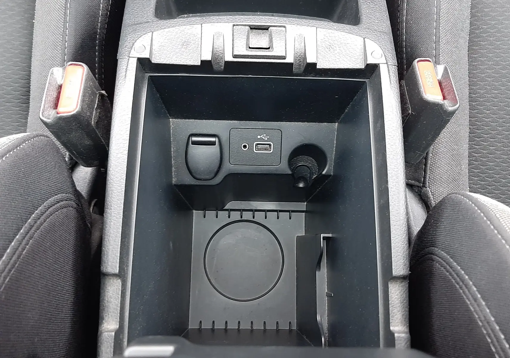 Vue plongeante sur le rangement central noir du Nissan Qashqai 2020, avec prise USB et porte-gobelet visible.