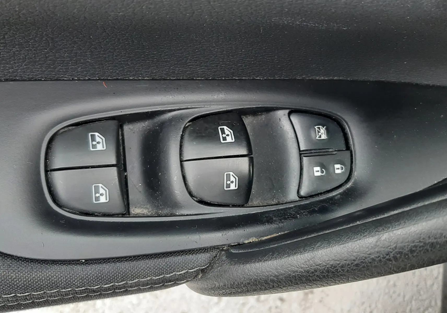 Gros plan sur les commandes de lève-vitres et verrouillage sur la porte côté conducteur d’un Nissan Qashqai noir 2020.