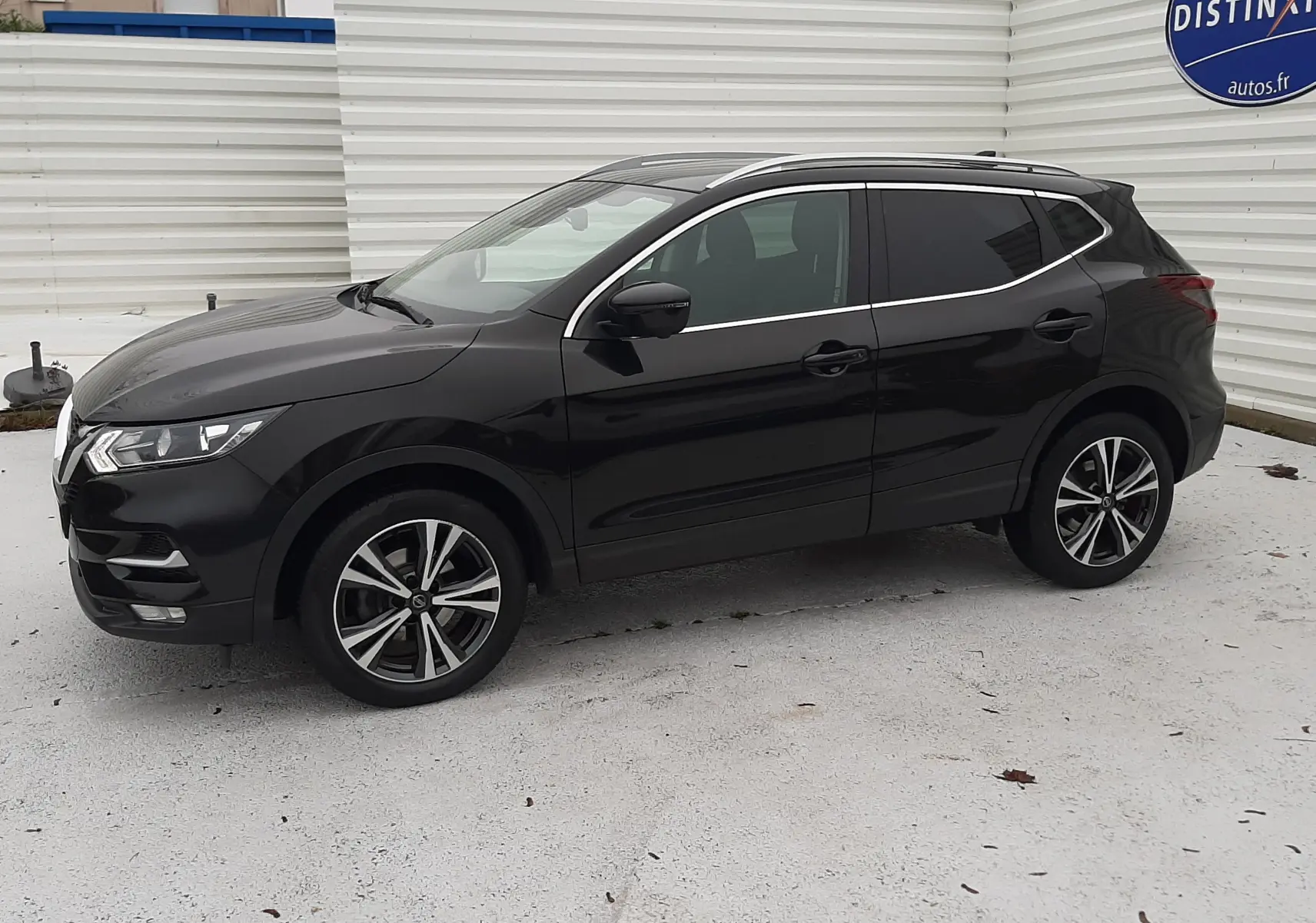 Nissan Qashqai DCI 115 N-Connecta noir en vue de profil côté gauche, avec jantes alliage bicolores et toit ouvrant.