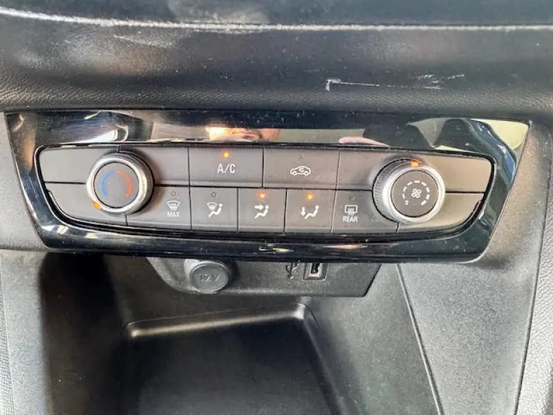 Panneau de commande de climatisation avec réglages manuels et voyants allumés dans une Opel Corsa bleu voltaïque métallisé.