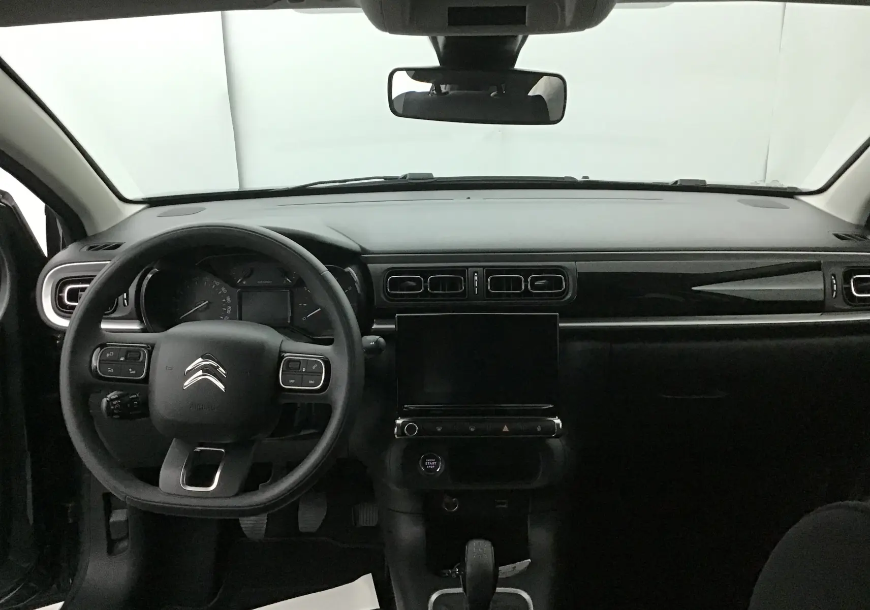 Vue intérieure frontale du tableau de bord noir brillant et volant multifonction de la Citroën C3 2022.