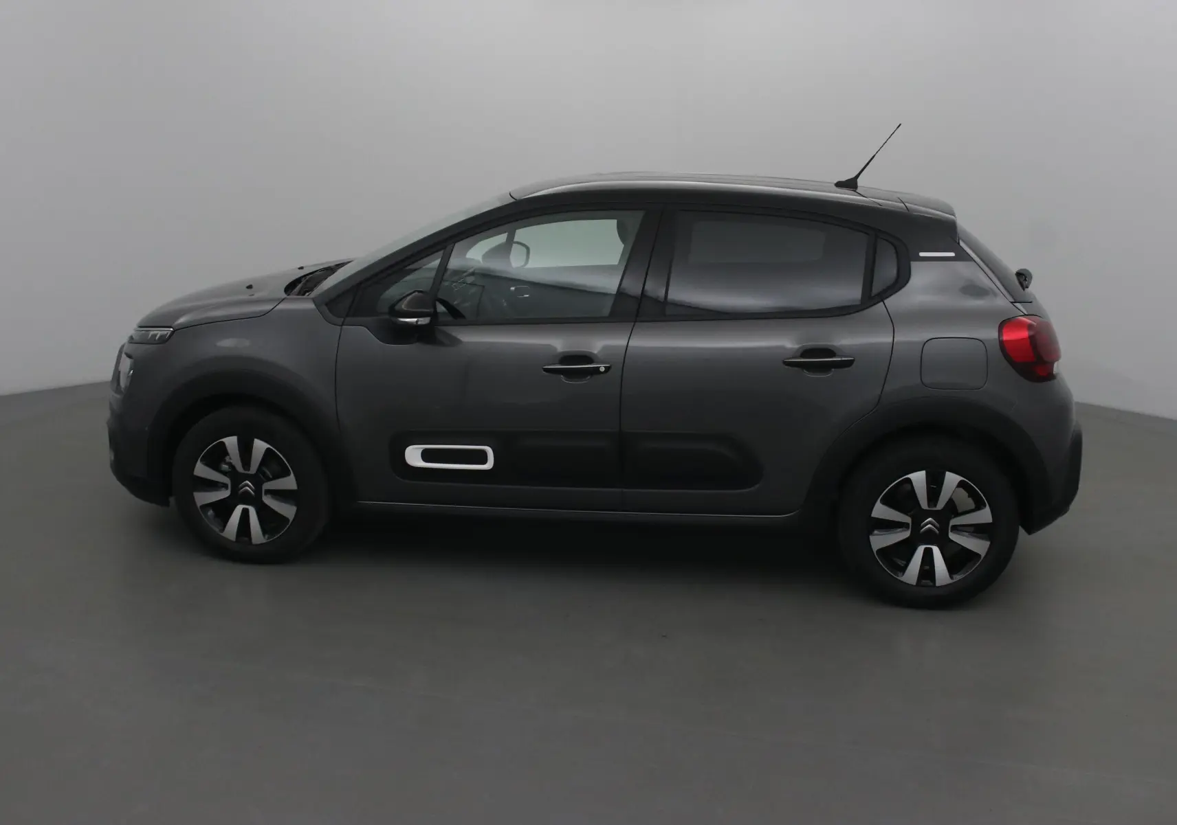 Profil côté gauche d'une Citroën C3 2022 gris platinium avec protections noires et jantes biton de 16 pouces.