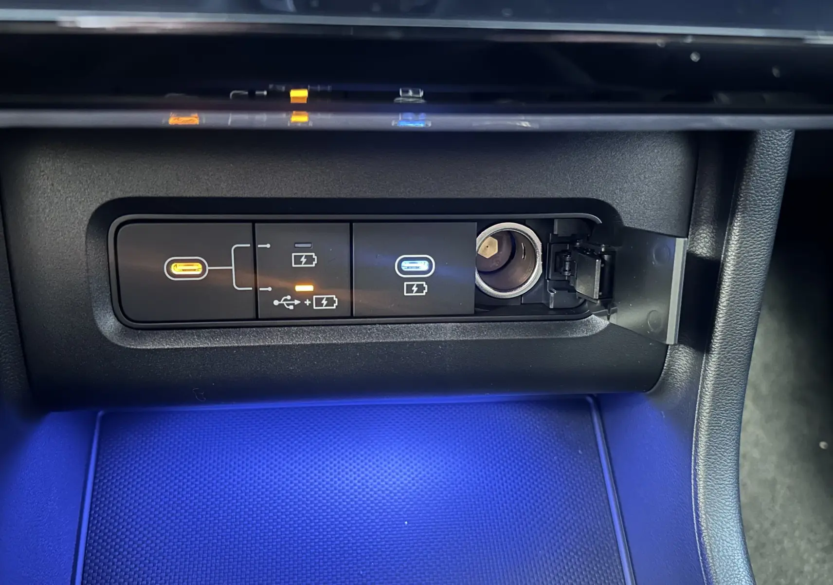Gros plan sur la console centrale du Hyundai Tucson 2025, montrant les ports USB et prise 12V avec éclairage bleu.