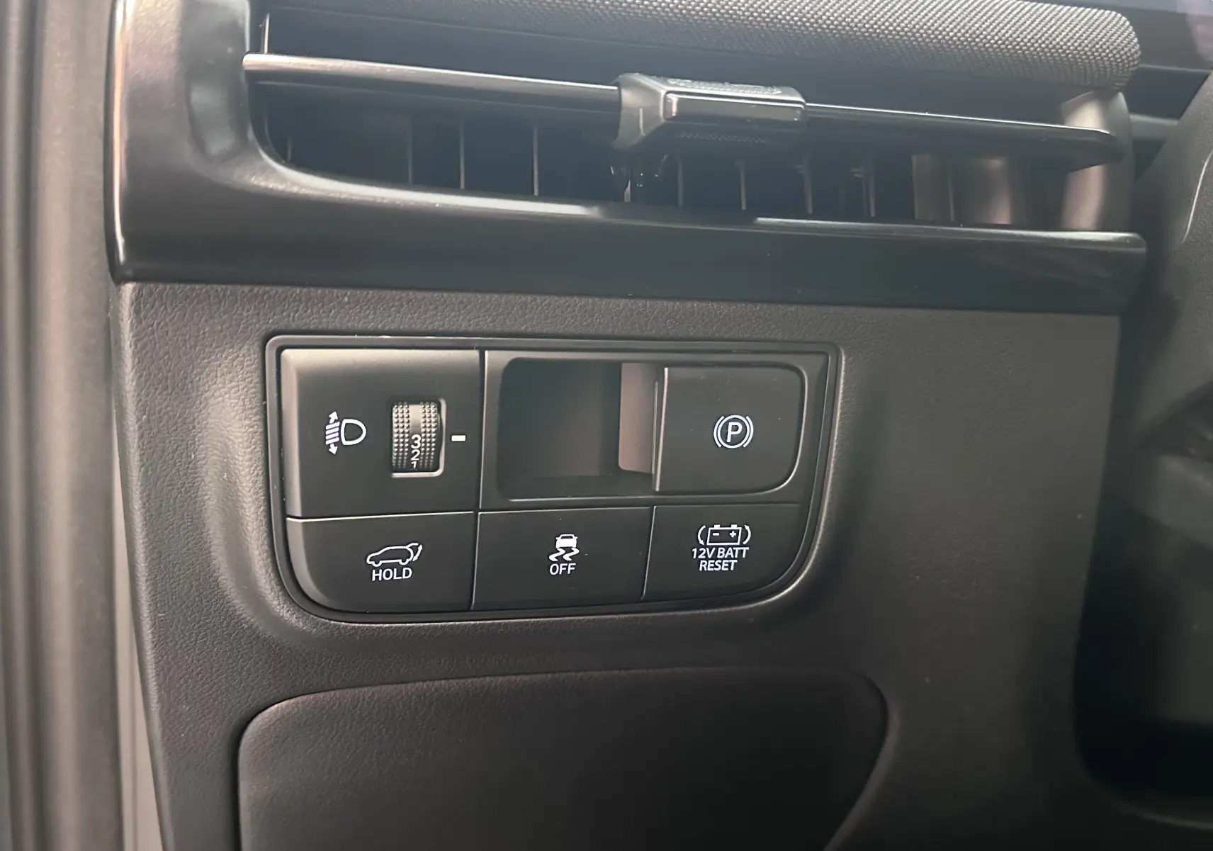 Gros plan sur les commandes noires côté gauche du tableau de bord du Hyundai Tucson 2025, avec boutons d'assistance et réglages lumineux.