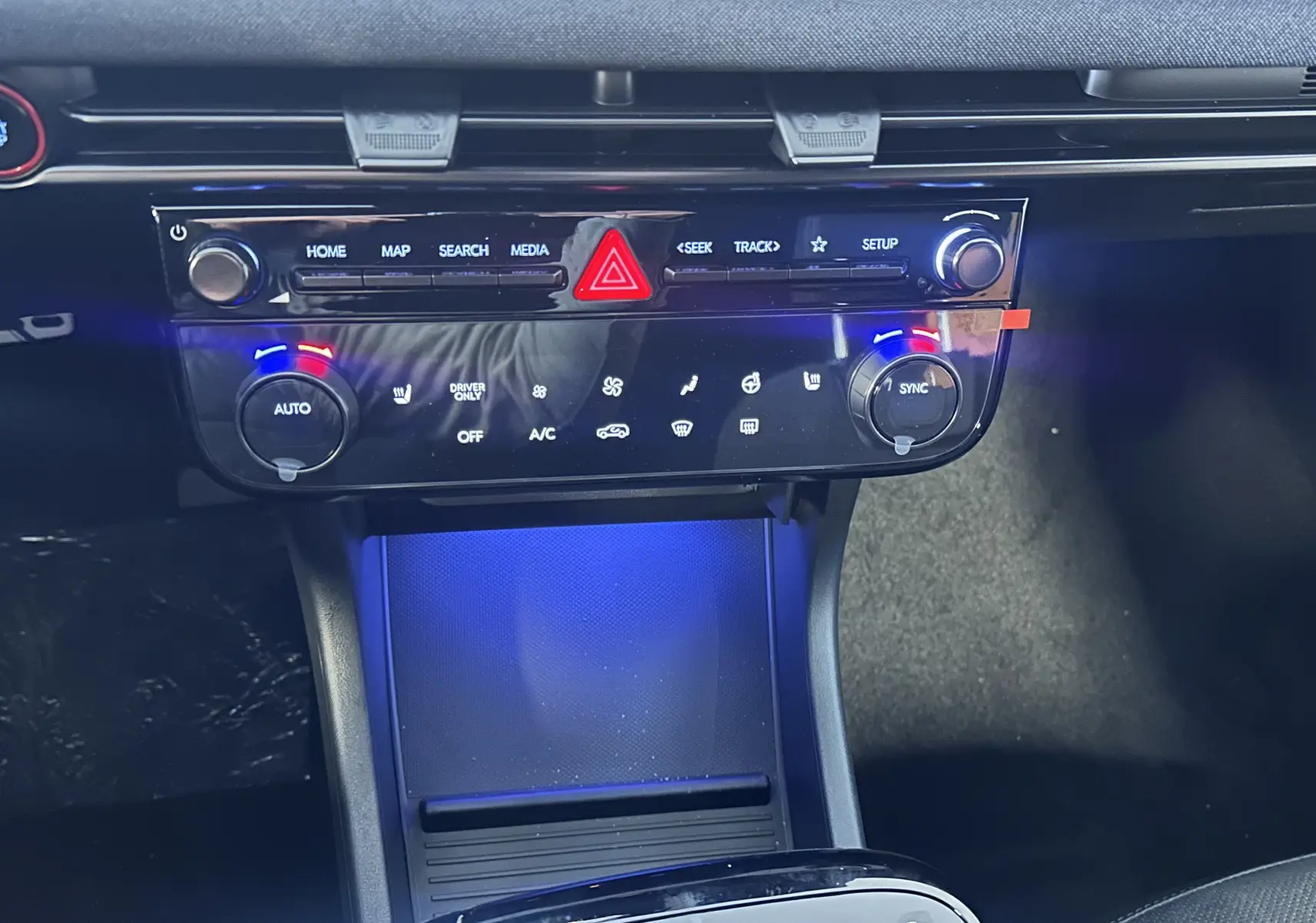 Vue rapprochée de la console centrale du Hyundai Tucson 2025, avec éclairage bleu et commandes tactiles noires.