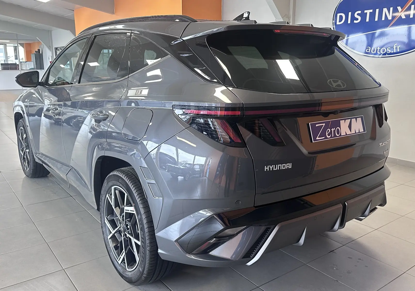 Vue 3/4 arrière droite du Hyundai Tucson gris Ecotronic avec feux arrière LED et jantes sport en concession.
