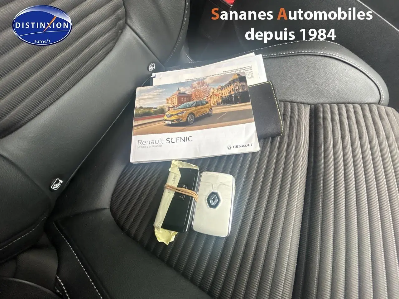 Vue rapprochée de la sellerie noire du Renault Scenic 2020 avec clés et notice d'utilisation posées dessus.