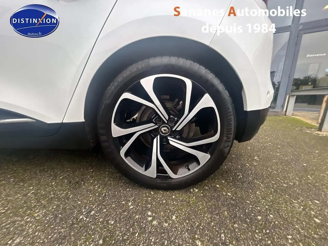 Gros plan sur la roue avant droite en jante alliage 20'' Quartz du Renault Scénic blanc nacré.