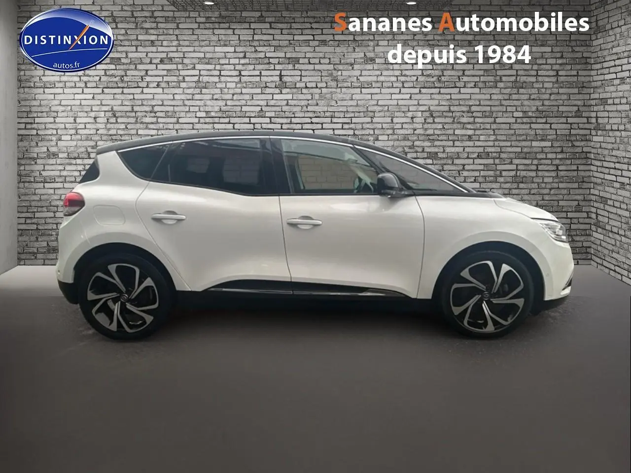 Profil droit d'un Renault Scénic blanc nacré avec toit noir étoilé et jantes alliage 20 pouces dans un showroom.