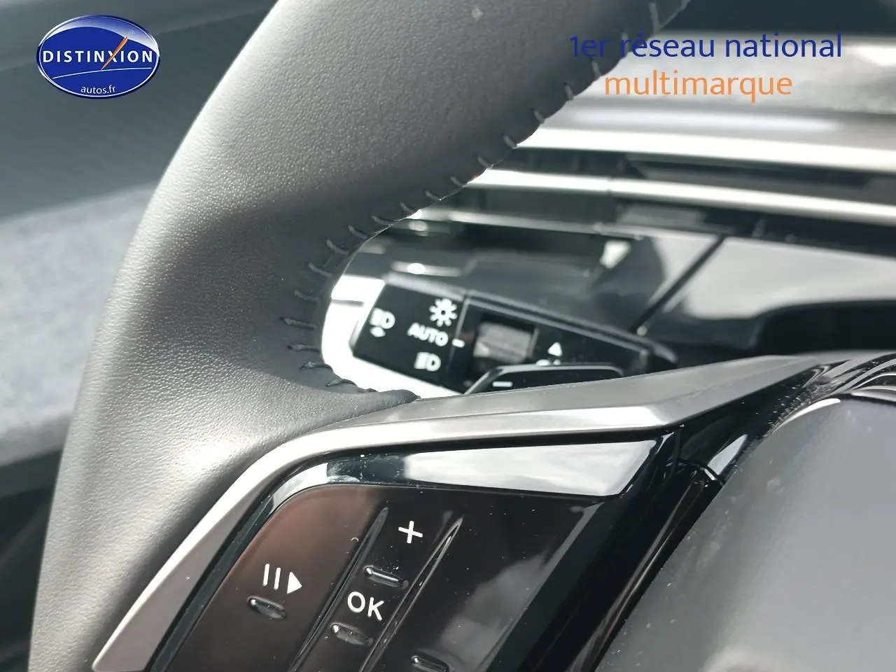 Gros plan sur les commandes multifonctions noires du volant cuir d’une Peugeot 3008 bleu, intérieur moderne.