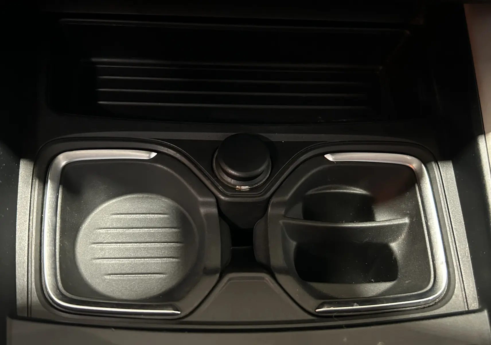 Gros plan sur les porte-gobelets centraux noirs avec contours chromés dans une BMW Série 1 gris diesel de 2014.