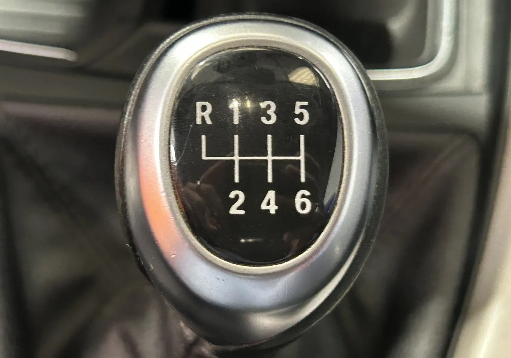 Gros plan sur le levier de vitesses manuel 6 rapports d'une BMW Série 1 16d gris, montrant la grille des vitesses.