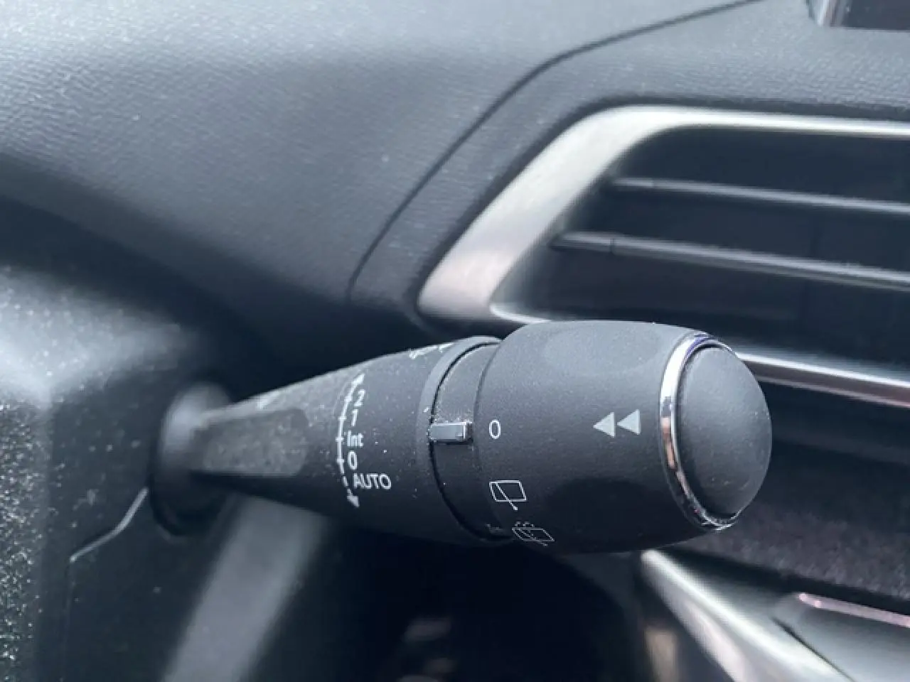Gros plan sur la commande d’essuie-glace à gauche du volant dans l’habitacle du Peugeot 3008 blanc 2017.