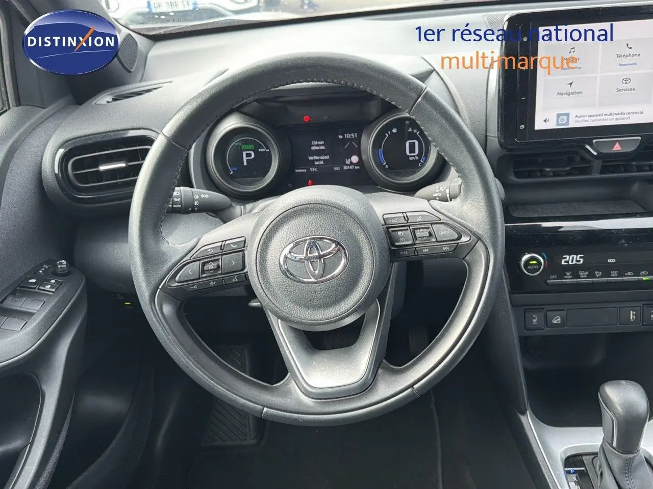 Vue intérieure centrée sur le volant et tableau de bord de la Toyota Yaris Cross gris minéral, avec écran tactile et commandes intégrées.