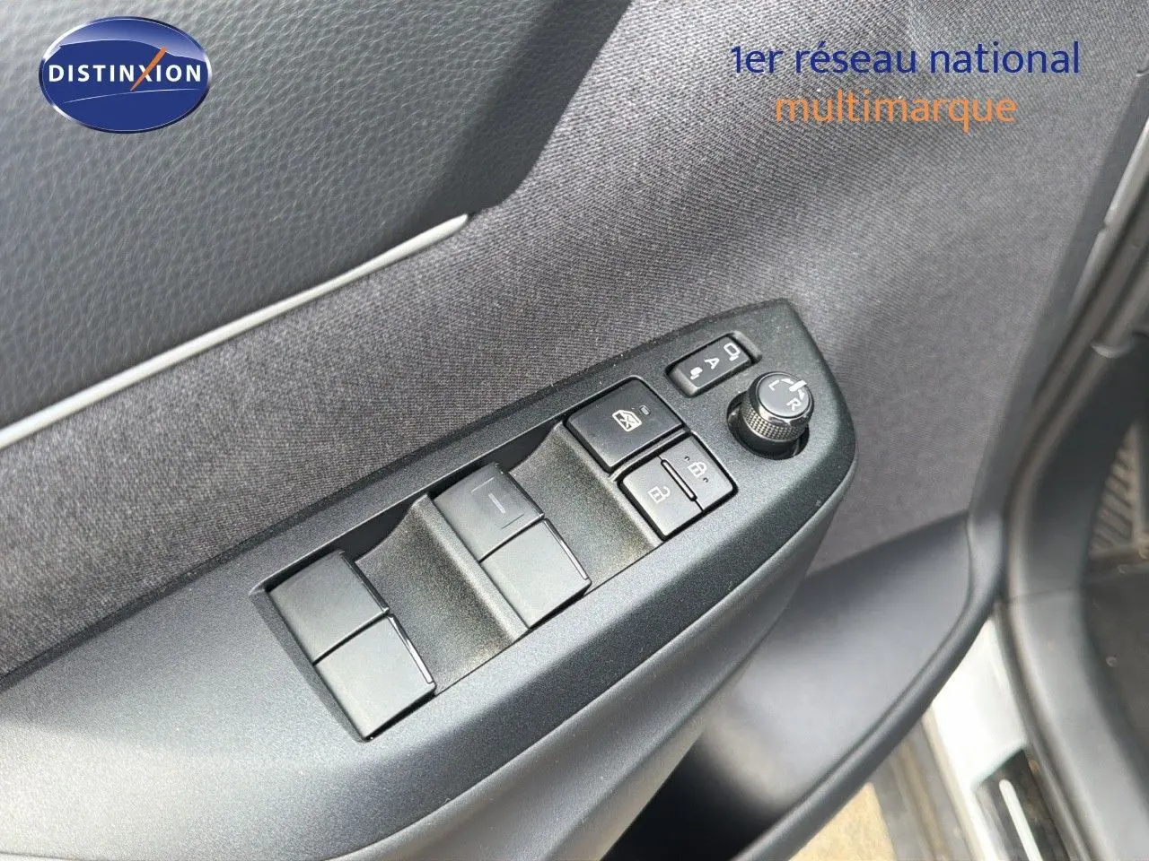 Gros plan sur les commandes des vitres et rétroviseurs côté gauche de la porte d'une Toyota Yaris Cross gris minéral 2023.